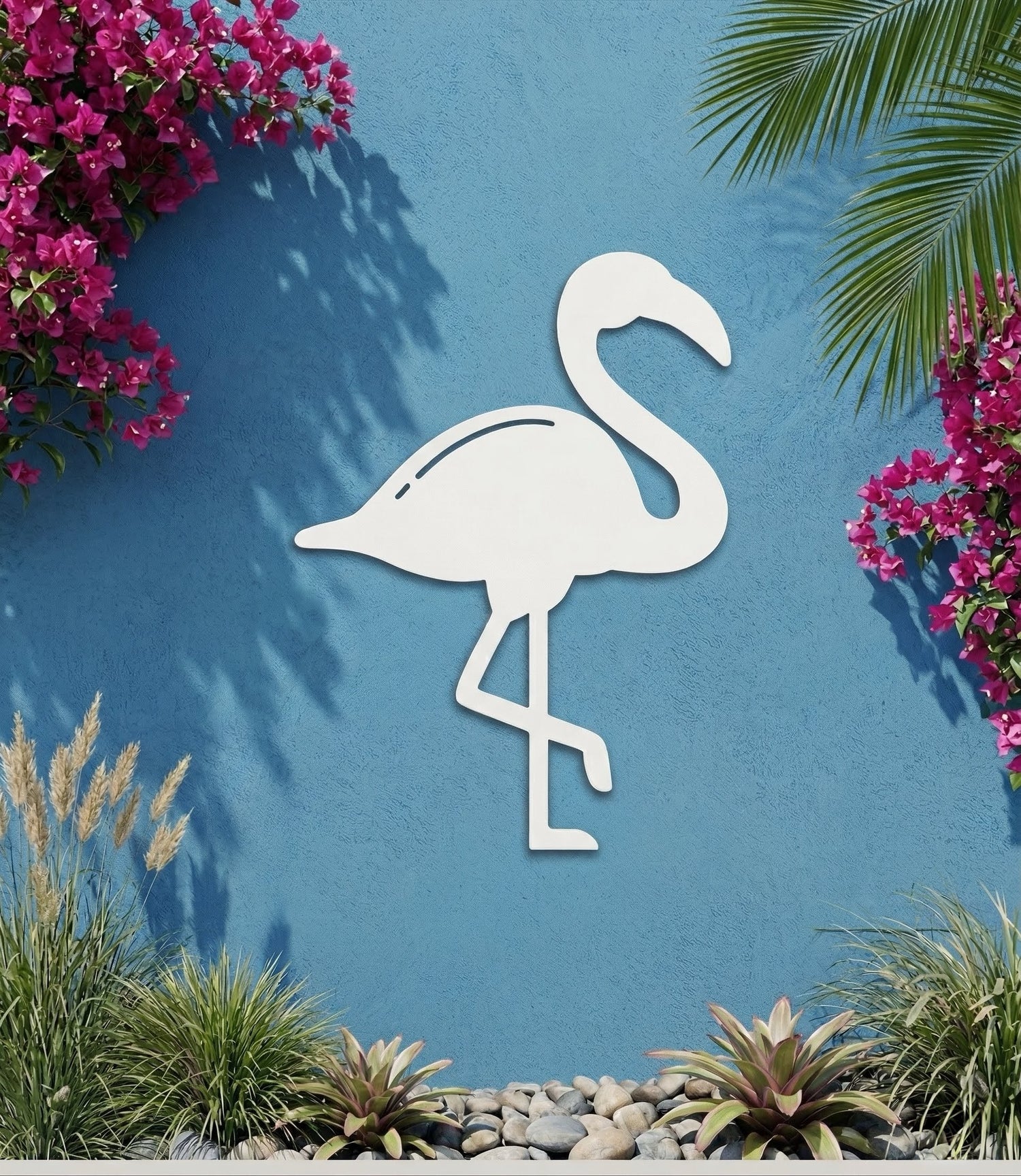 White PVC flamingo decorative wall art on a blue wall with pink flowers and greenery.