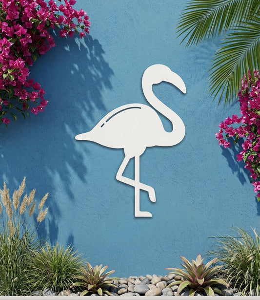 White PVC flamingo decorative wall art on a blue wall with pink flowers and greenery.